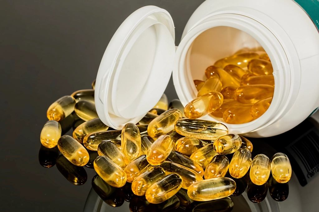 Supplement capsules spilling from an open bottle